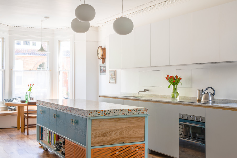 Moderne Wohnküche mit Arbeitsplatte aus Terrazzo, braunem Holzboden, Kücheninsel, braunem Boden und grauer Arbeitsplatte in London