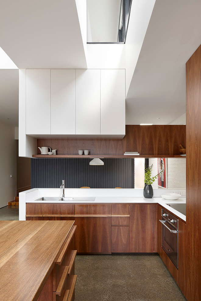 Design ideas for a medium sized contemporary l-shaped kitchen in Melbourne with a submerged sink, flat-panel cabinets, stainless steel appliances, travertine flooring, an island and dark wood cabinets.