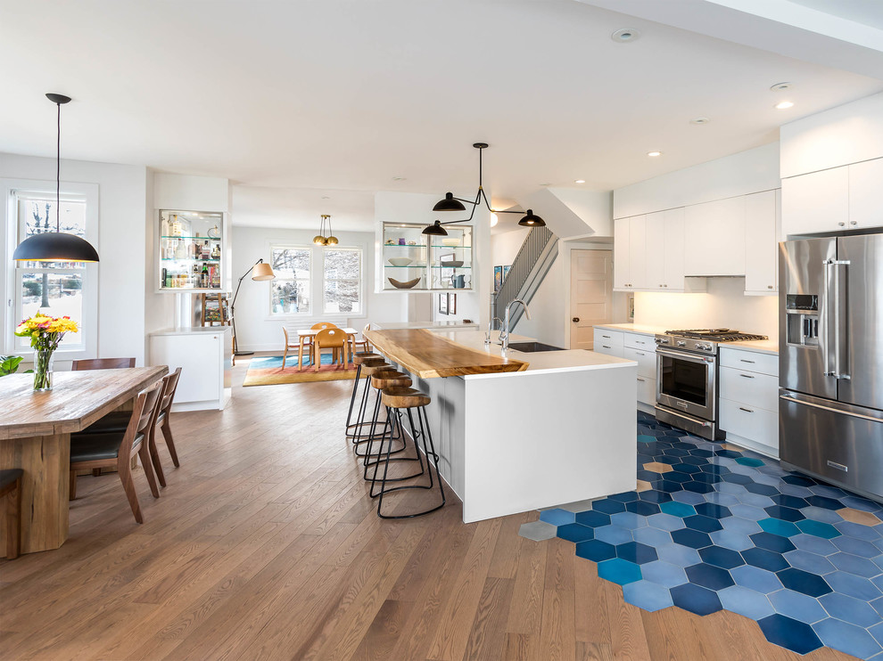 Foto på ett funkis vit kök med öppen planlösning, med en rustik diskho, släta luckor, vita skåp, bänkskiva i kvarts, vitt stänkskydd, stänkskydd i sten, rostfria vitvaror, cementgolv, en köksö och blått golv