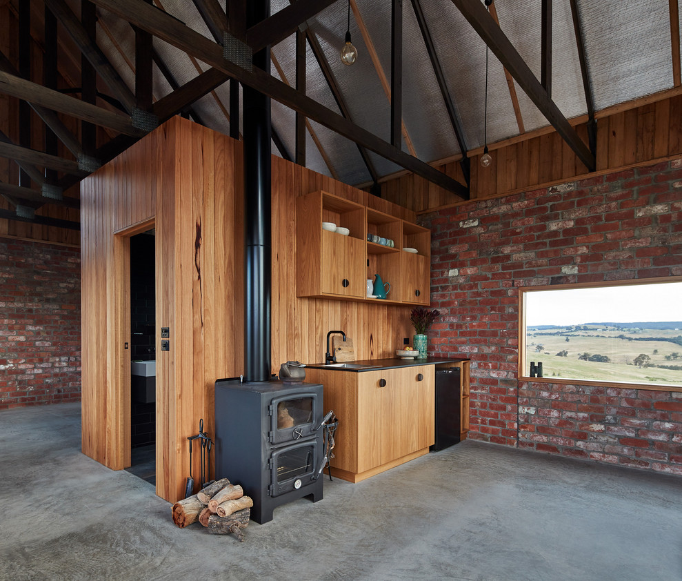Idéer för att renovera ett avskilt, litet rustikt svart linjärt svart kök, med en undermonterad diskho, luckor med infälld panel, skåp i ljust trä, stänkskydd i trä, svarta vitvaror, betonggolv och grått golv