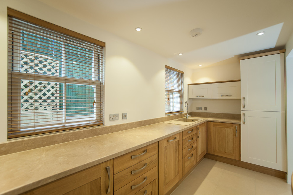Exempel på ett litet modernt kök, med en nedsänkt diskho, luckor med upphöjd panel, skåp i mellenmörkt trä, marmorbänkskiva, beige stänkskydd, stänkskydd i skiffer, rostfria vitvaror, klinkergolv i keramik, en halv köksö och beiget golv
