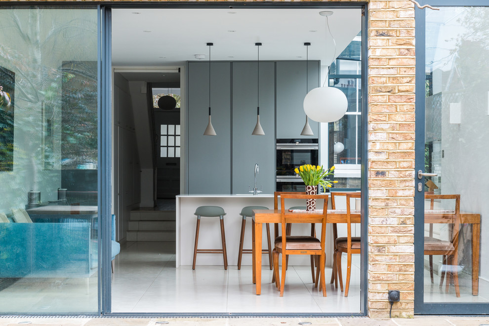 Свежая идея для дизайна: большая прямая кухня в стиле фьюжн с обеденным столом, плоскими фасадами, серыми фасадами, полом из керамической плитки и полуостровом - отличное фото интерьера