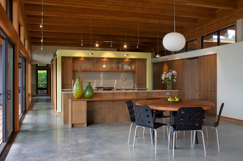 Aménagement d'une cuisine américaine parallèle moderne en bois brun avec un placard à porte vitrée, une crédence grise, une crédence en carreau de verre et un électroménager en acier inoxydable.