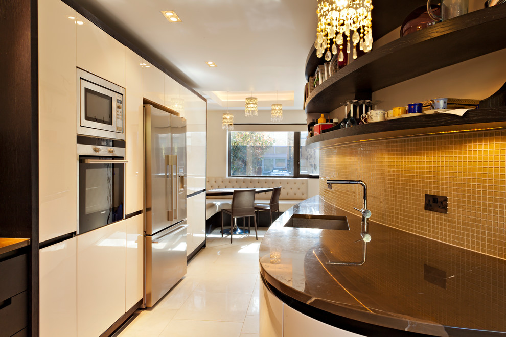Example of a trendy galley ceramic tile eat-in kitchen design in London with an undermount sink, flat-panel cabinets, white cabinets, yellow backsplash, glass tile backsplash, stainless steel appliances and no island