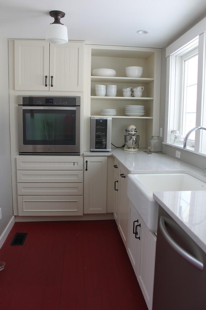 Kleine Landhausstil Küche mit Landhausspüle, weißen Schränken, Quarzwerkstein-Arbeitsplatte, Küchengeräten aus Edelstahl und gebeiztem Holzboden in New York