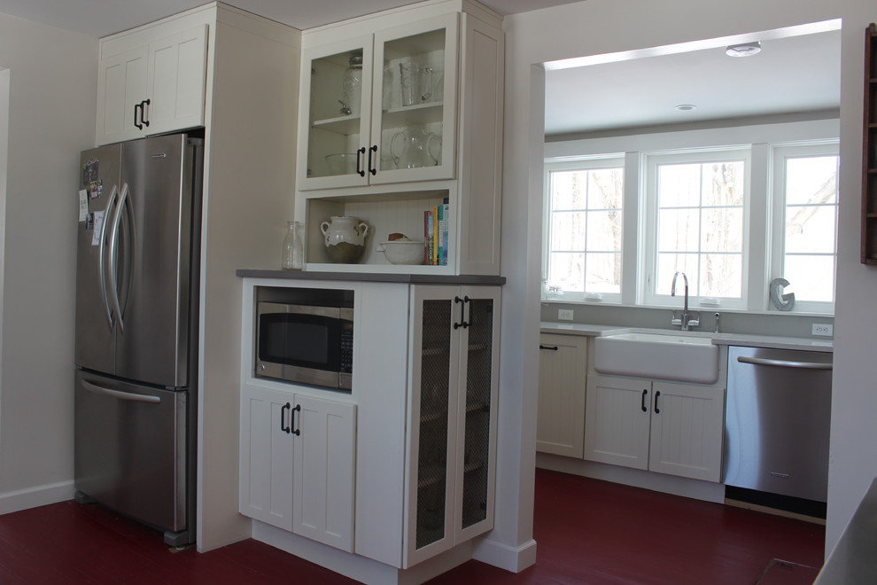 Lantlig inredning av ett litet kök, med en rustik diskho, vita skåp, bänkskiva i kvarts, rostfria vitvaror och målat trägolv