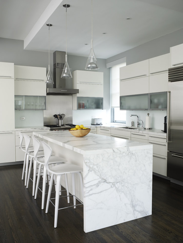 Inspiration for a contemporary l-shaped kitchen remodel in New York with stainless steel appliances, glass-front cabinets, white cabinets and marble countertops