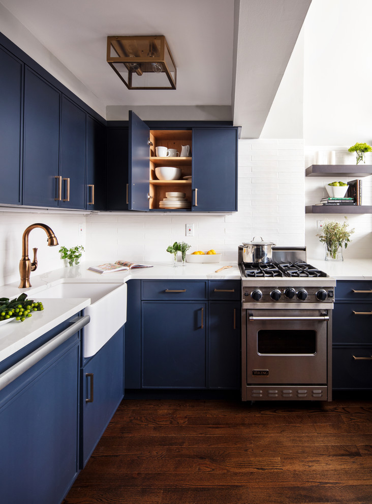 Inspiration for a small contemporary kitchen in New York with a belfast sink, blue cabinets, white splashback, stainless steel appliances, dark hardwood flooring, brown floors, white worktops, flat-panel cabinets, quartz worktops, metro tiled splashback and no island.