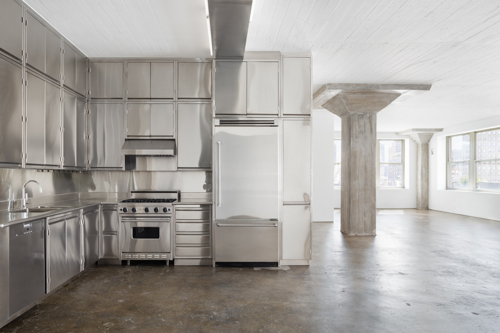 Immagine di una cucina minimalista con lavello integrato, ante lisce, ante in acciaio inossidabile, top in acciaio inossidabile, paraspruzzi grigio, elettrodomestici in acciaio inossidabile e pavimento in cemento
