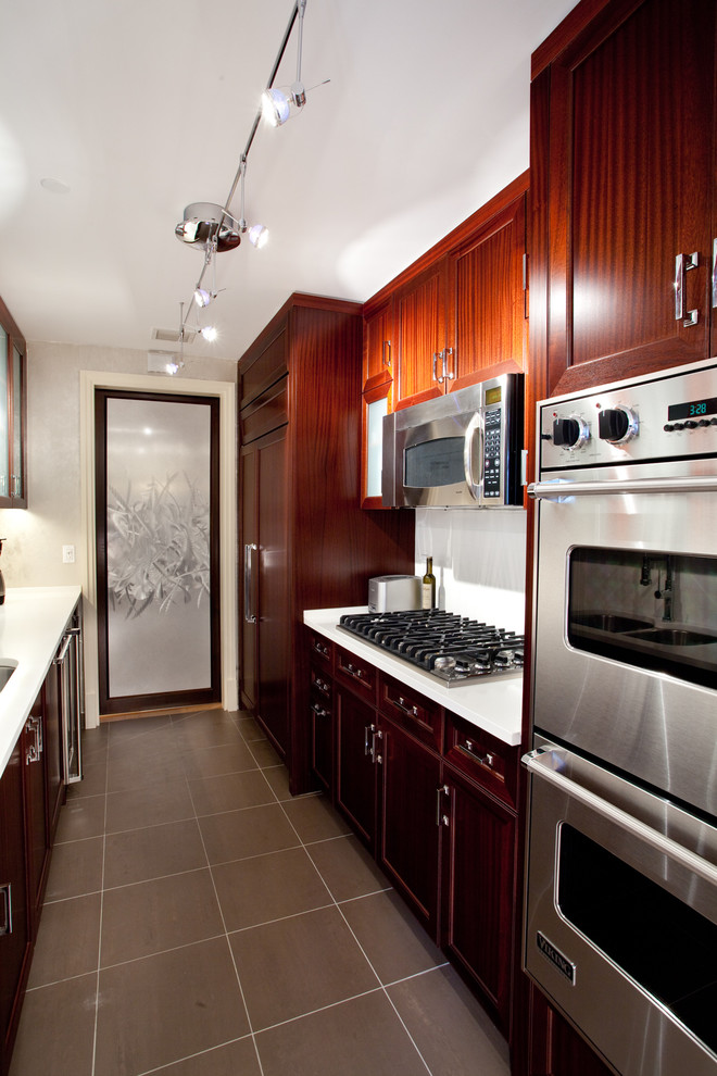 Foto di una piccola cucina parallela chic con lavello sottopiano, ante in legno scuro, paraspruzzi bianco, elettrodomestici in acciaio inossidabile e nessuna isola