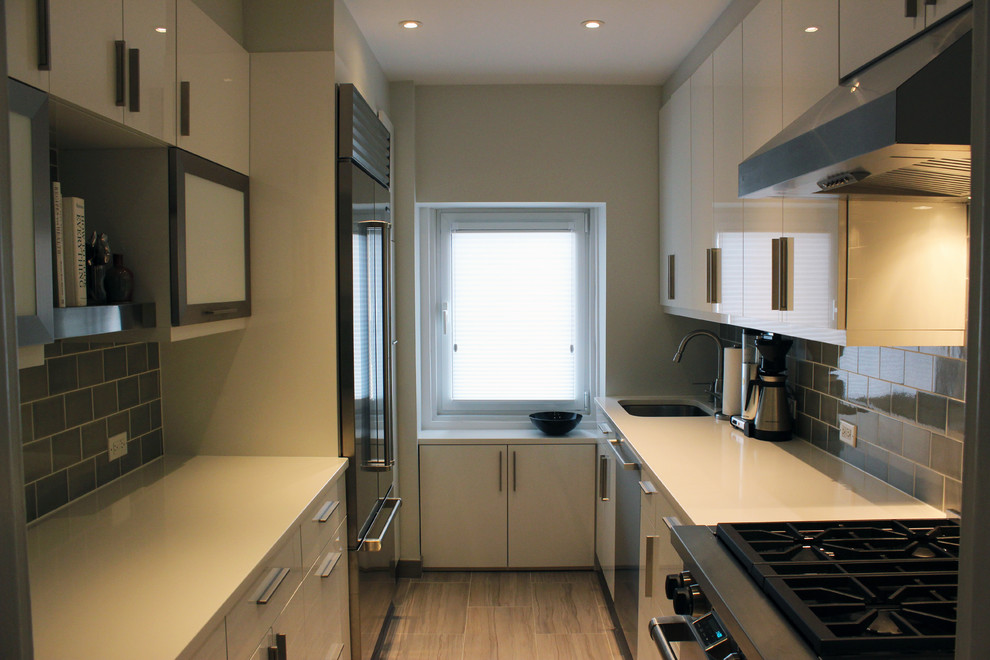 Inspiration pour une cuisine parallèle design de taille moyenne avec un placard à porte plane, des portes de placard blanches et un électroménager en acier inoxydable.