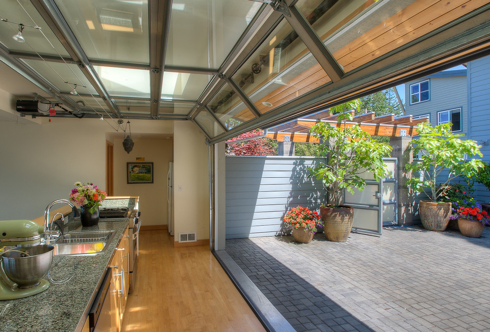 Inspiration for a mid-sized coastal single-wall light wood floor kitchen remodel in Seattle with a drop-in sink, flat-panel cabinets, brown cabinets, granite countertops, green backsplash, stone slab backsplash, stainless steel appliances, no island and green countertops