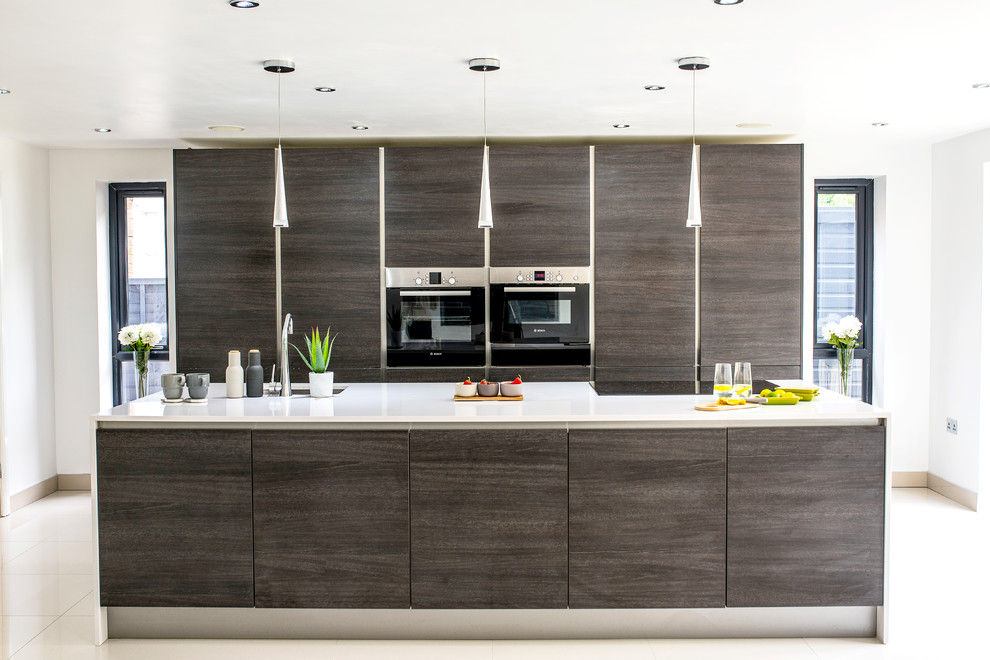 Large contemporary galley kitchen in Other with a single-bowl sink, flat-panel cabinets, dark wood cabinets, quartz worktops, black appliances, porcelain flooring, an island, white floors and white worktops.