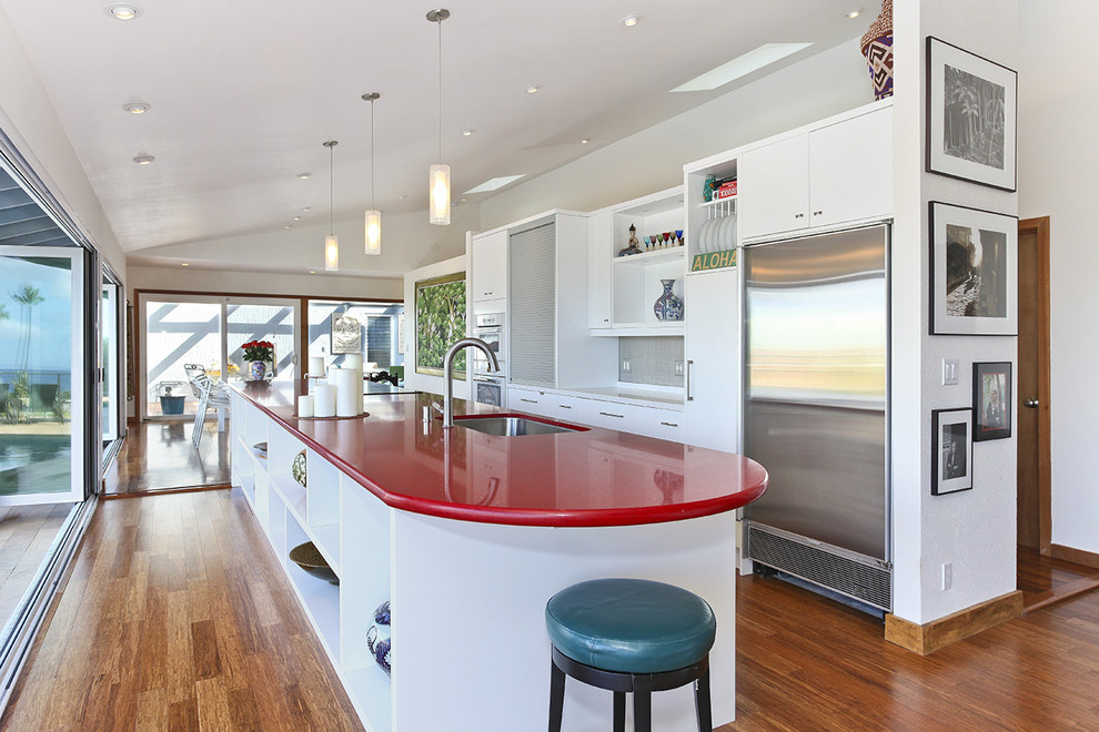 Example of a mid-sized trendy single-wall dark wood floor and brown floor enclosed kitchen design in Hawaii with an undermount sink, flat-panel cabinets, white cabinets, stainless steel appliances, an island, quartz countertops and red countertops
