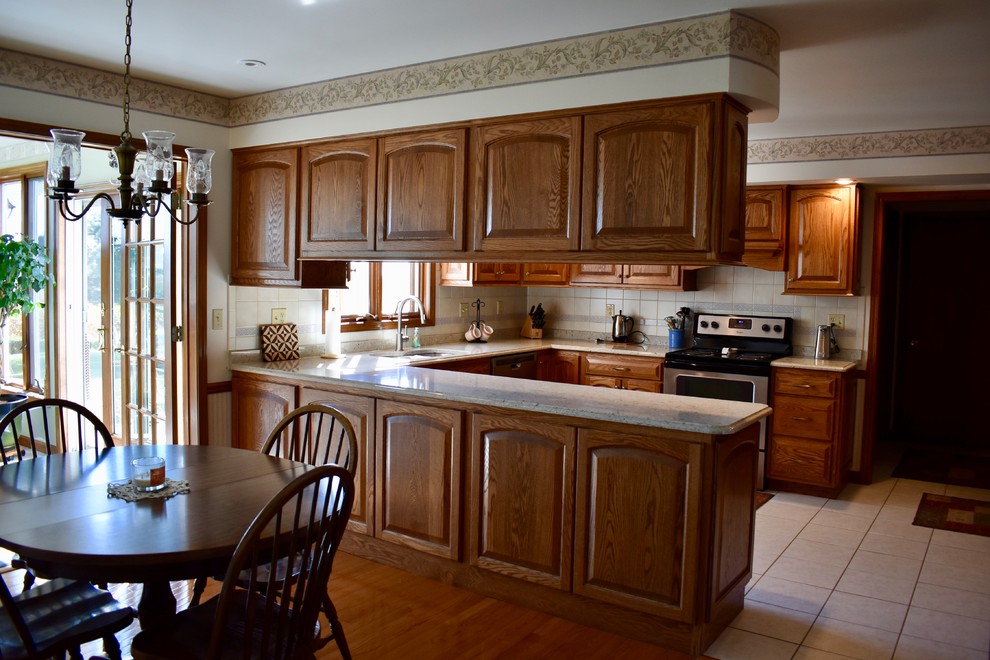 Klassische Küche in U-Form mit profilierten Schrankfronten, hellbraunen Holzschränken, Quarzwerkstein-Arbeitsplatte und Küchengeräten aus Edelstahl in Chicago