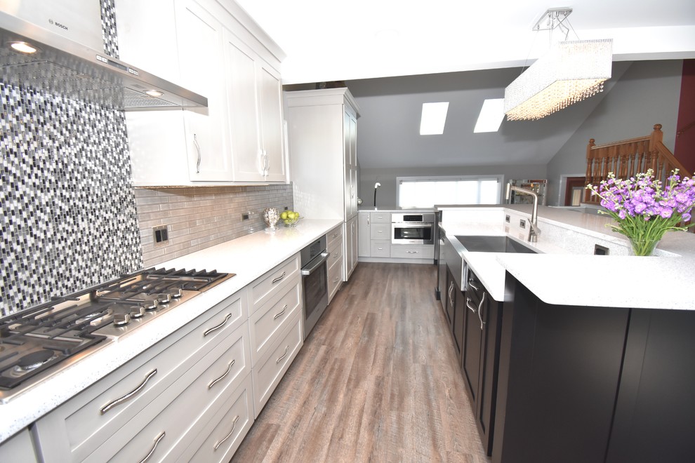 Bild på ett stort eklektiskt grå grått kök, med en rustik diskho, skåp i shakerstil, orange skåp, bänkskiva i kvarts, grått stänkskydd, stänkskydd i glaskakel, rostfria vitvaror, vinylgolv, en köksö och brunt golv
