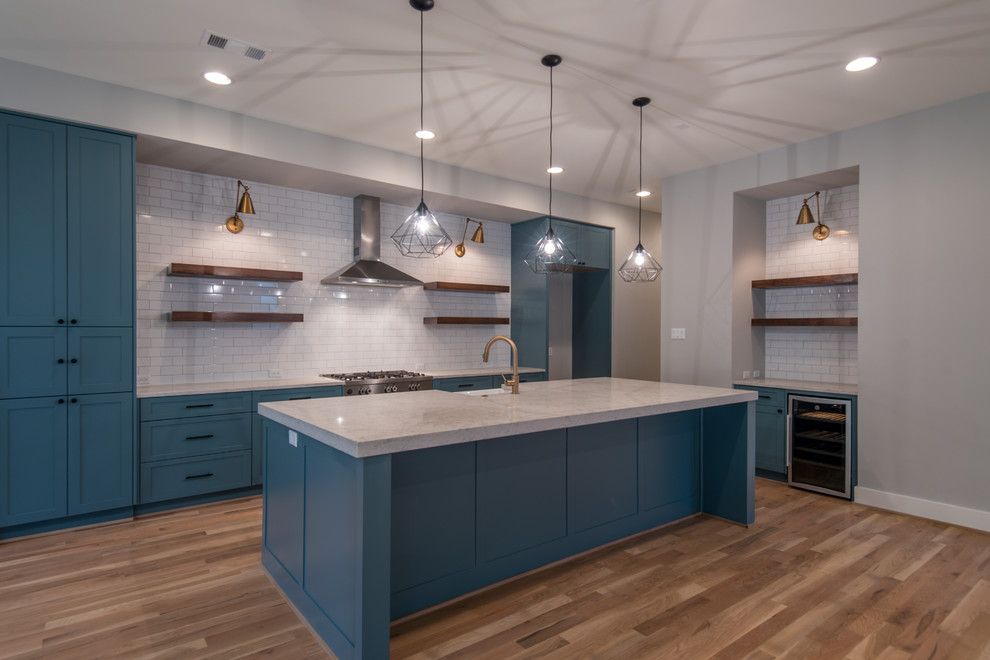 Eat-in kitchen - country single-wall light wood floor and brown floor eat-in kitchen idea in Houston with a farmhouse sink, shaker cabinets, blue cabinets, quartz countertops, white backsplash, subway tile backsplash, stainless steel appliances, an island and white countertops