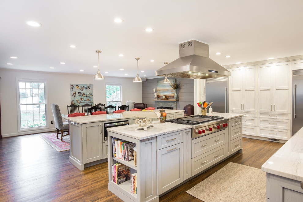 Bild på ett stort vintage linjärt kök och matrum, med en undermonterad diskho, skåp i shakerstil, vita skåp, marmorbänkskiva, flerfärgad stänkskydd, stänkskydd i stickkakel, rostfria vitvaror, mellanmörkt trägolv, flera köksöar och brunt golv