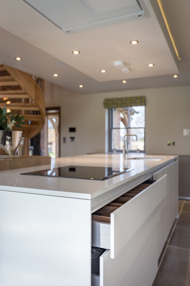 Large contemporary single-wall kitchen/diner in Other with a single-bowl sink, flat-panel cabinets, white cabinets, quartz worktops, black appliances, porcelain flooring and an island.