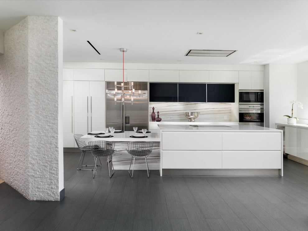 Inspiration for a contemporary l-shaped kitchen/diner in Miami with flat-panel cabinets, white cabinets, white splashback, stainless steel appliances, an island, stone slab splashback and dark hardwood flooring.