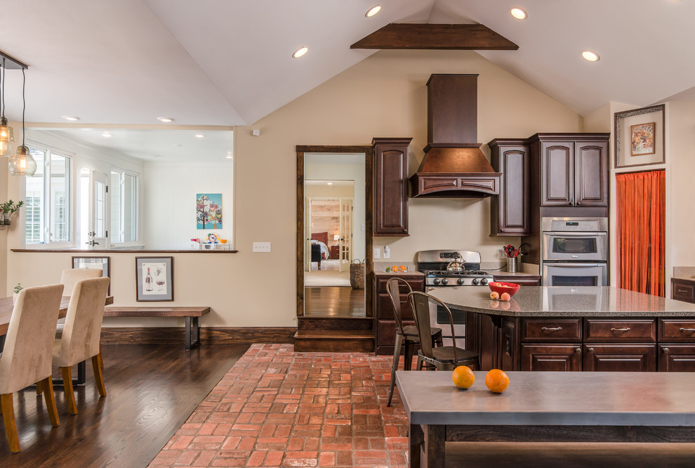 ナッシュビルにあるおしゃれなキッチン (レイズドパネル扉のキャビネット、濃色木目調キャビネット、シルバーの調理設備、レンガの床) の写真