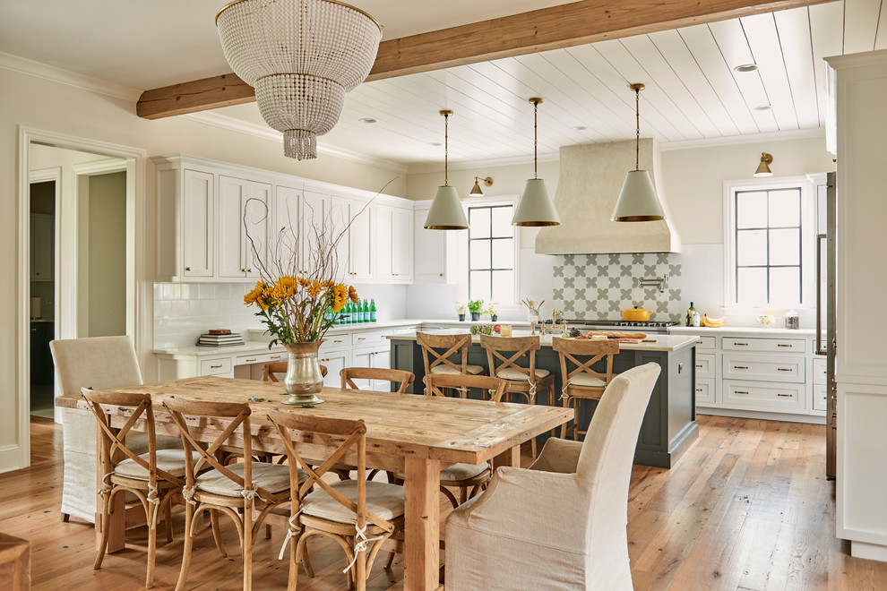 Country u-shaped open plan kitchen in Other with shaker cabinets, white cabinets, white splashback, stainless steel appliances, medium hardwood flooring, an island and brown floors.