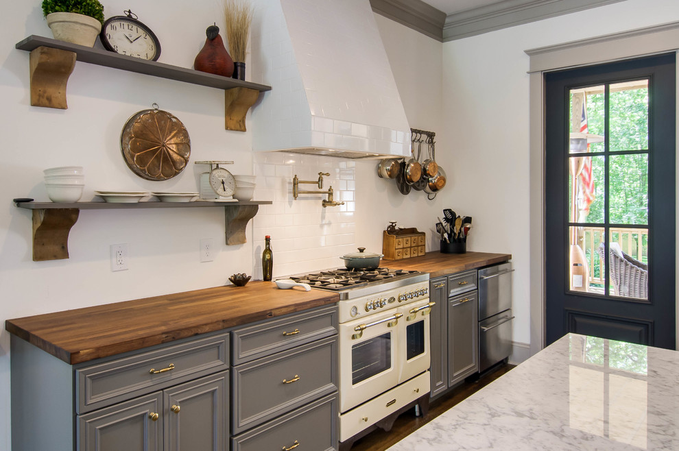 Imagen de cocina gris y blanca tradicional renovada con armarios con paneles empotrados, puertas de armario grises, encimera de madera, salpicadero blanco y salpicadero de azulejos tipo metro