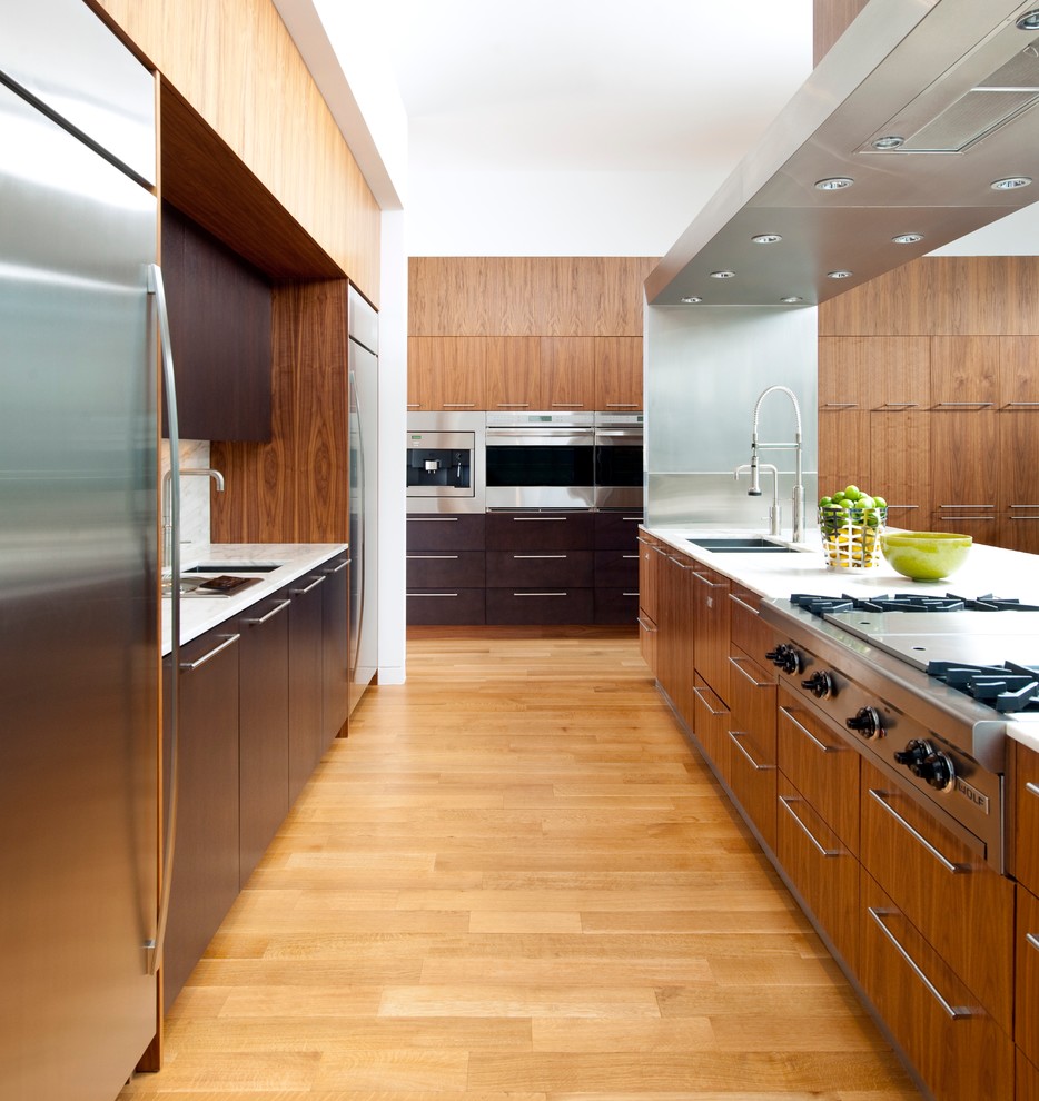 Exempel på ett mycket stort modernt kök, med släta luckor, skåp i mellenmörkt trä, mellanmörkt trägolv, en dubbel diskho, bänkskiva i kvarts, vitt stänkskydd, rostfria vitvaror och en köksö