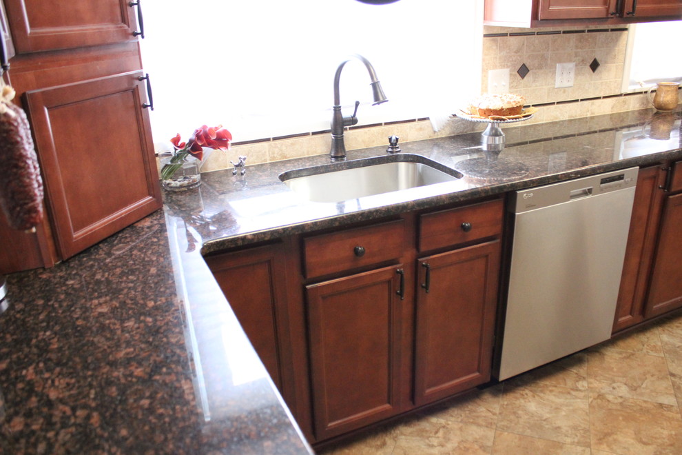 Exempel på ett mellanstort klassiskt kök och matrum, med en undermonterad diskho, luckor med infälld panel, skåp i mellenmörkt trä, granitbänkskiva, flerfärgad stänkskydd, stänkskydd i stenkakel, rostfria vitvaror och klinkergolv i keramik