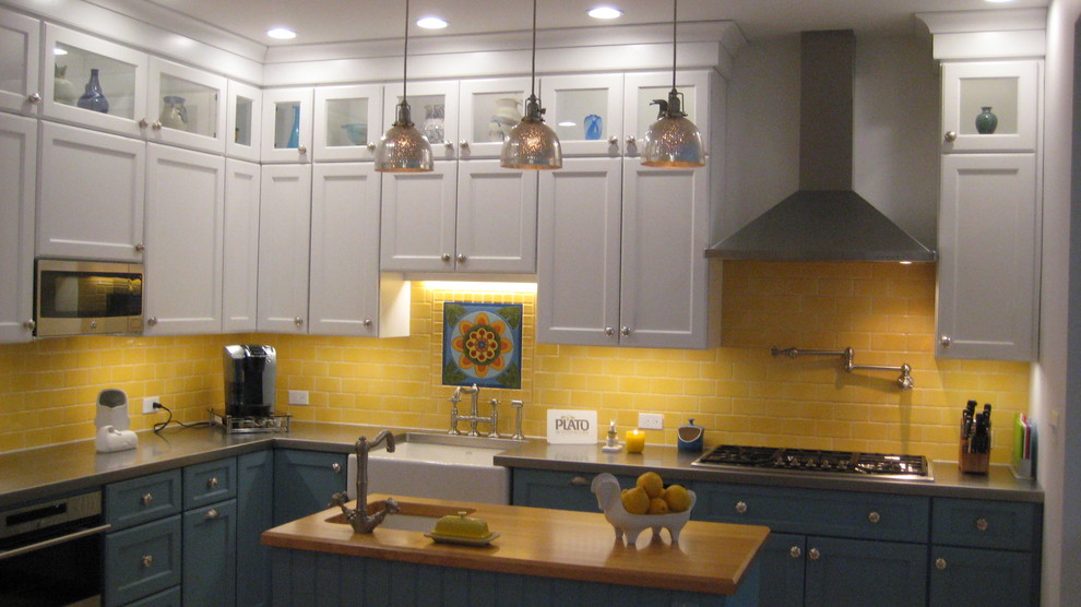 Rural l-shaped enclosed kitchen in Chicago with a belfast sink, shaker cabinets, white cabinets, wood worktops, yellow splashback, metro tiled splashback, stainless steel appliances and an island.