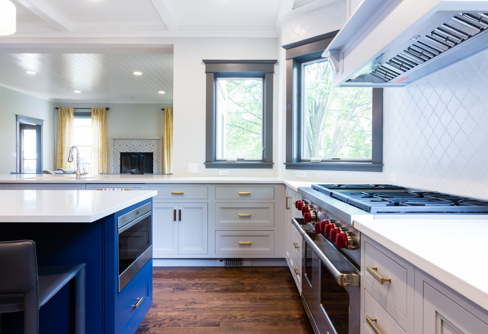 Photo of a traditional u-shaped open plan kitchen in Boston with an integrated sink, shaker cabinets, blue cabinets, granite worktops, white splashback, porcelain splashback, integrated appliances, dark hardwood flooring, an island and brown floors.