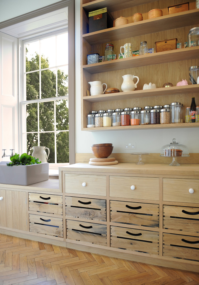 This is an example of a large farmhouse l-shaped open plan kitchen in London with flat-panel cabinets, light wood cabinets, marble worktops, an island, a belfast sink and light hardwood flooring.