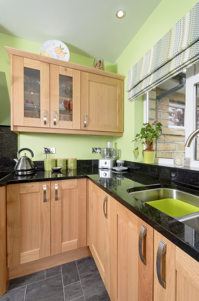 Medium sized classic kitchen in Other with shaker cabinets, light wood cabinets, composite countertops, black splashback, stainless steel appliances and a breakfast bar.