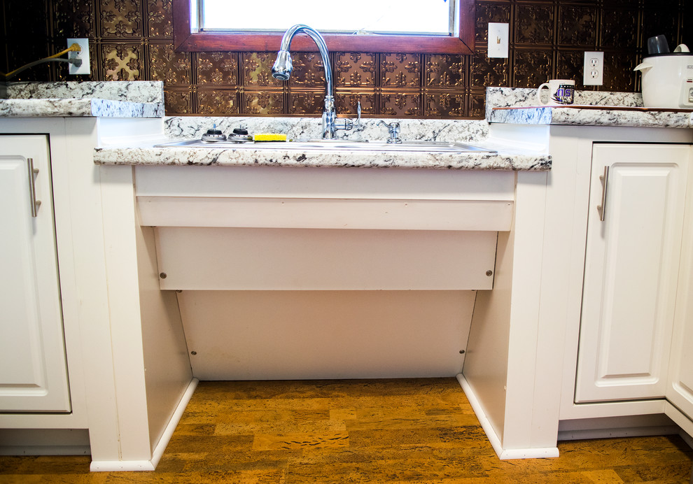 Bild på ett avskilt, mellanstort vintage u-kök, med en nedsänkt diskho, luckor med upphöjd panel, vita skåp, granitbänkskiva, brunt stänkskydd, stänkskydd i metallkakel, rostfria vitvaror och brunt golv