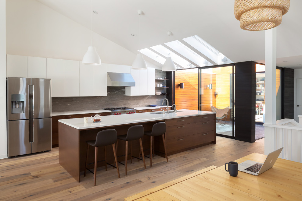 Photo of a medium sized contemporary galley kitchen in San Francisco with a submerged sink, flat-panel cabinets, dark wood cabinets, grey splashback, stainless steel appliances, medium hardwood flooring and an island.