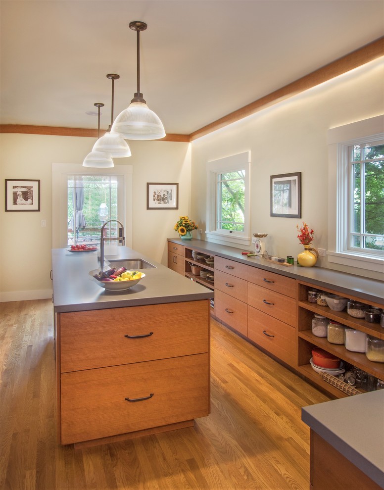 Example of a mid-sized transitional l-shaped medium tone wood floor and brown floor enclosed kitchen design in San Francisco with an undermount sink, flat-panel cabinets, medium tone wood cabinets, solid surface countertops, stainless steel appliances, an island and gray countertops