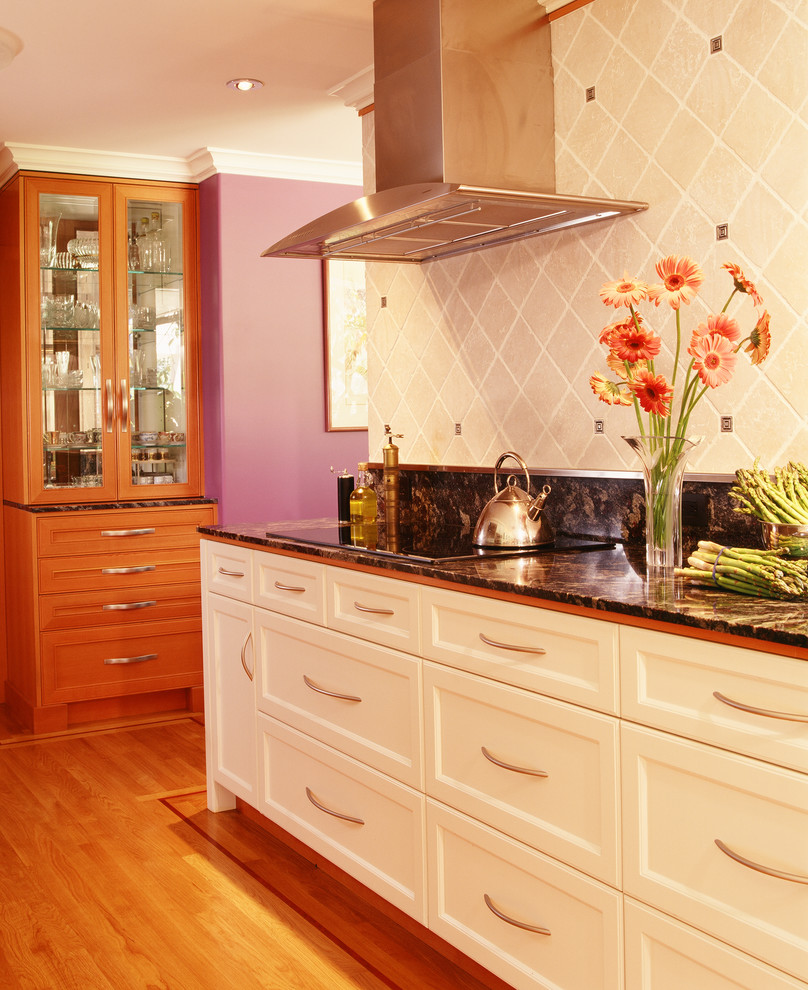 Inredning av ett modernt kök, med en undermonterad diskho, luckor med infälld panel, skåp i mellenmörkt trä, granitbänkskiva, vitt stänkskydd, stänkskydd i stenkakel, rostfria vitvaror och mellanmörkt trägolv