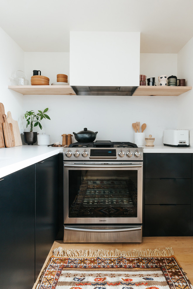 This is an example of a scandinavian l-shaped kitchen in San Francisco with white splashback, flat-panel cabinets, stainless steel appliances, light hardwood flooring and white worktops.