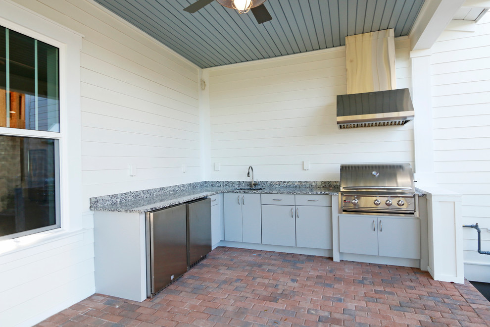 На фото: угловая кухня среднего размера в классическом стиле с врезной мойкой, плоскими фасадами, серыми фасадами, техникой из нержавеющей стали и кирпичным полом с