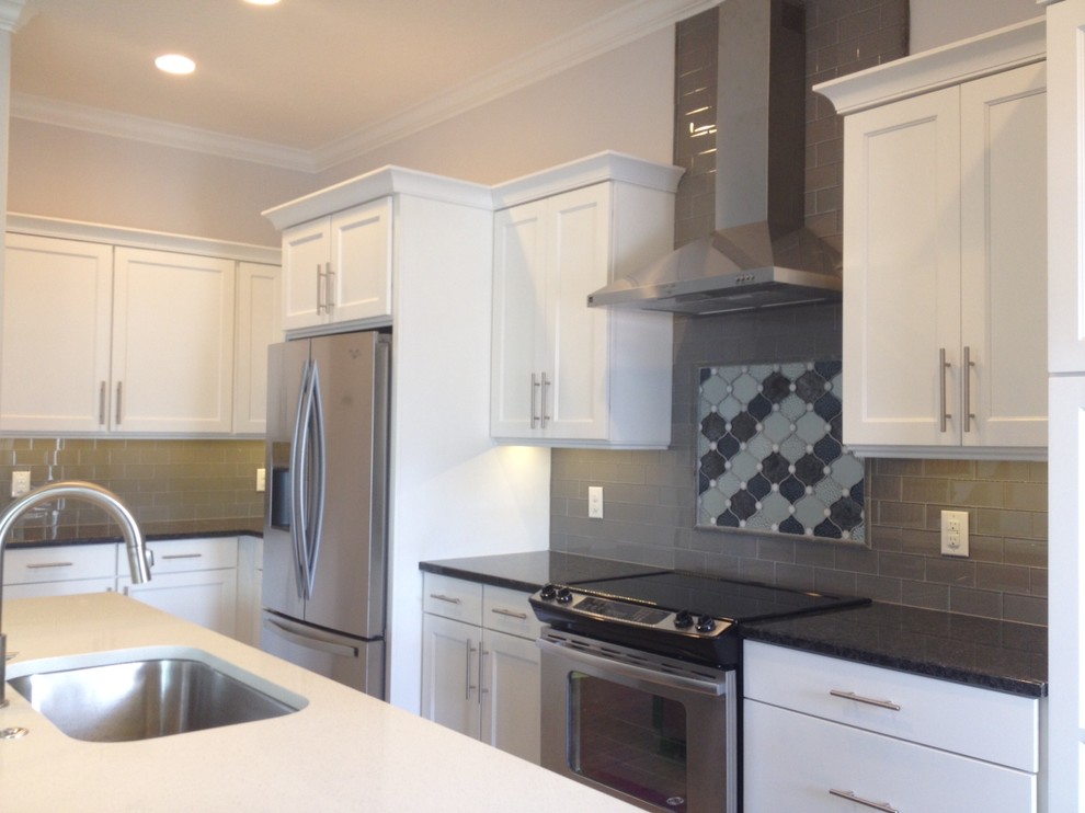 Inredning av ett modernt mellanstort kök, med en enkel diskho, luckor med infälld panel, vita skåp, bänkskiva i kvarts, svart stänkskydd, stänkskydd i keramik, rostfria vitvaror och en köksö