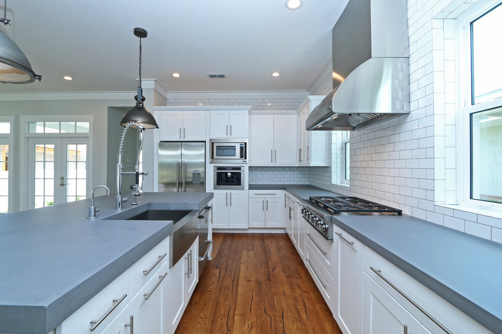 Exempel på ett mellanstort modernt kök, med en rustik diskho, luckor med infälld panel, vita skåp, bänkskiva i betong, vitt stänkskydd, stänkskydd i tunnelbanekakel, rostfria vitvaror, mellanmörkt trägolv och en köksö