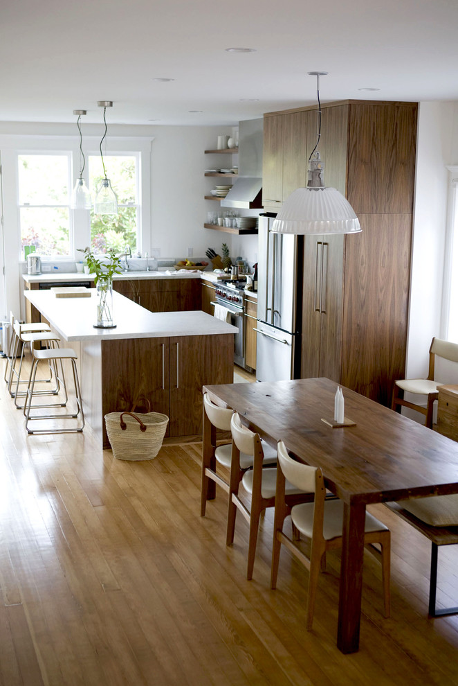 Inredning av ett modernt mellanstort kök, med en undermonterad diskho, släta luckor, skåp i mellenmörkt trä, marmorbänkskiva, rostfria vitvaror, ljust trägolv, en köksö, grått stänkskydd, stänkskydd i sten och brunt golv