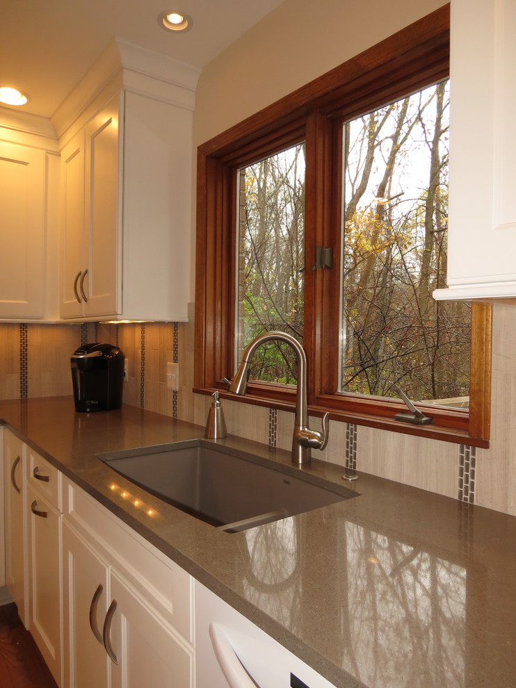 Foto på ett mellanstort funkis kök och matrum, med en undermonterad diskho, släta luckor, vita skåp, grått stänkskydd, stänkskydd i stenkakel, vita vitvaror, mellanmörkt trägolv, en köksö och bänkskiva i återvunnet glas