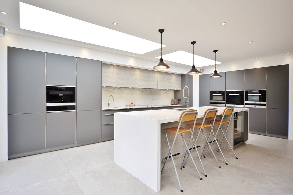 Exempel på ett stort modernt vit vitt l-kök, med en undermonterad diskho, släta luckor, grå skåp, bänkskiva i kvartsit, vitt stänkskydd, stänkskydd i sten, svarta vitvaror, klinkergolv i porslin, en köksö och grått golv