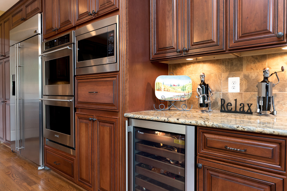 Bild på ett mellanstort vintage kök, med en undermonterad diskho, luckor med upphöjd panel, skåp i mörkt trä, granitbänkskiva, beige stänkskydd, stänkskydd i stenkakel, rostfria vitvaror, mellanmörkt trägolv och en köksö