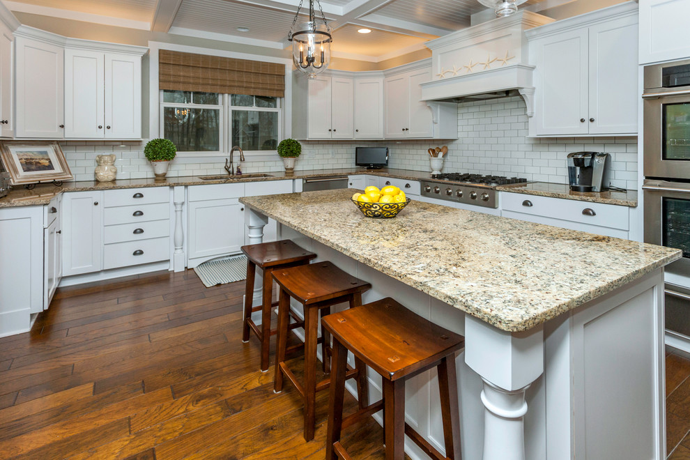 Large arts and crafts u-shaped medium tone wood floor eat-in kitchen photo in Other with an undermount sink, flat-panel cabinets, white cabinets, granite countertops, white backsplash, subway tile backsplash, stainless steel appliances and an island