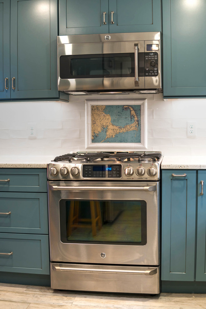 Inredning av ett modernt litet kök, med en rustik diskho, skåp i shakerstil, blå skåp, bänkskiva i återvunnet glas, vitt stänkskydd, stänkskydd i keramik, rostfria vitvaror, klinkergolv i keramik, en köksö och beiget golv