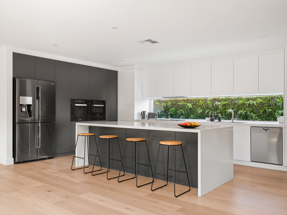 Inspiration for a large modern l-shaped open plan kitchen in Sydney with a double-bowl sink, open cabinets, dark wood cabinets, composite countertops, white splashback, window splashback, black appliances, light hardwood flooring, an island, brown floors and white worktops.