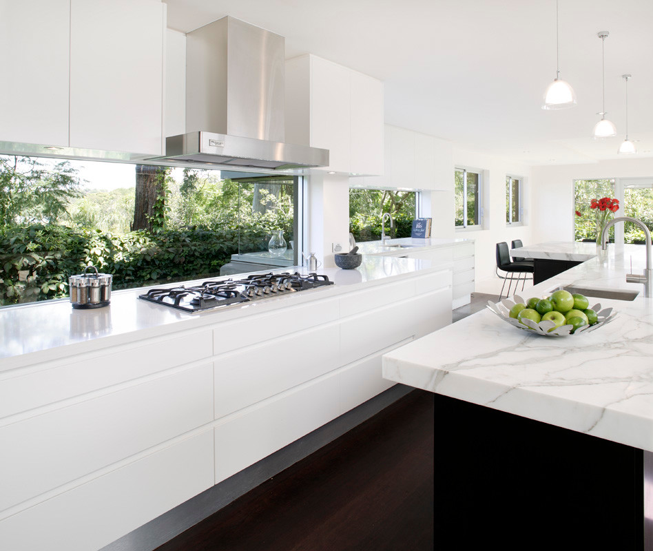 Einzeilige, Große Moderne Wohnküche mit flächenbündigen Schrankfronten, Marmor-Arbeitsplatte, Küchengeräten aus Edelstahl, Waschbecken, weißen Schränken, Glasrückwand, dunklem Holzboden und Kücheninsel in Sydney