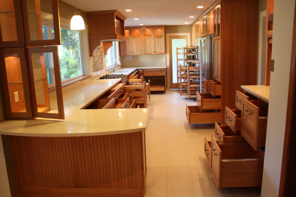 ポートランドにある高級なトラディショナルスタイルのおしゃれなキッチン (アンダーカウンターシンク、シェーカースタイル扉のキャビネット、中間色木目調キャビネット、クオーツストーンカウンター、シルバーの調理設備) の写真